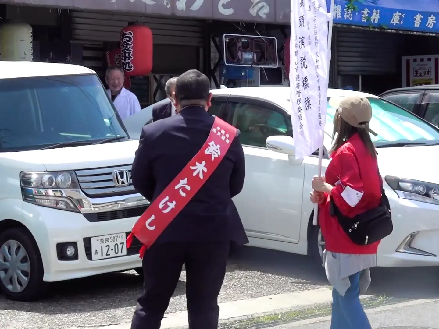 商店の前で地域の方に向き合う鈴木たけし