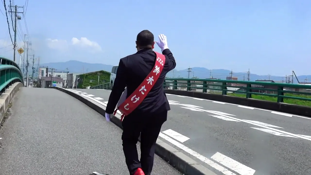 橋の歩道を歩きながら手を振る鈴木たけし